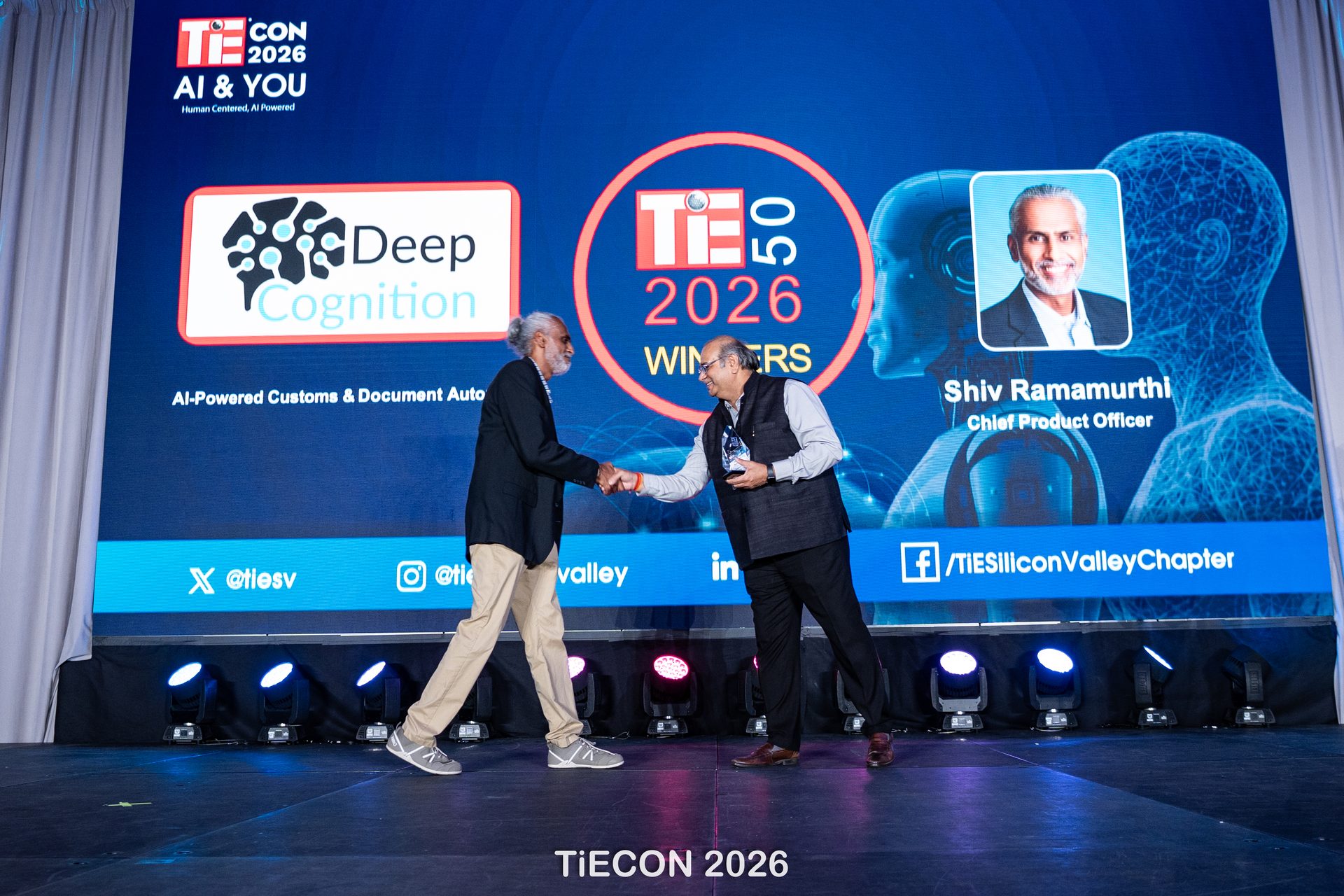 Shiv Ramamurthi shaking hands on stage as Deep Cognition is announced a TiE50 2026 winner